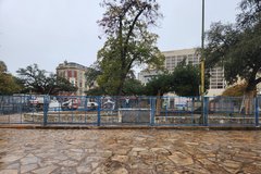Blue fencing around excavation area with Alamo Street in the background