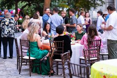 Guests seated at a table surrounded by standing guests enjoying the event