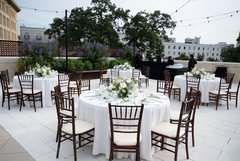 Tables set outside with white floral centerpieces and white linens
