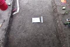 Smooth, dirt surface at bottom of excavation unit with a red pail in the corner