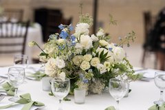 White floral centerpiece on a white linen surrounded by wine glasses