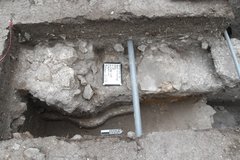 Pipe across a rock wall inside excavation unit