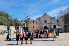 Color guard of women holding flags in front of Alamo Church