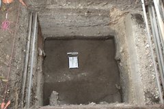 Dirt and a small white board inside of an excavation unit
