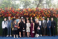 Large group of guests in black tie attire in front of a floral backdrop