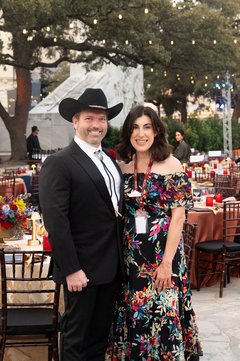 Man in black cowboy hat and tuxedo wtih a bolo with a woman in a dark floral gown