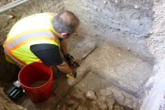 Archaeologist cleaning the compacted lime surface inside excavation unit