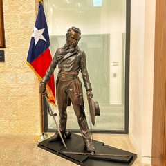 Bronze statue Lt. Colonel William Barret Travis drawing a line with a sword in front a Texas State flag