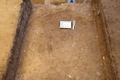 Smooth surface at bottom of excavation unit with a white board and ruler