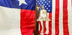 Bell against a Texas flag and a USA flag