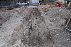 Excavation area in Alamo Plaza surrounded by fencing across from a white parked truck