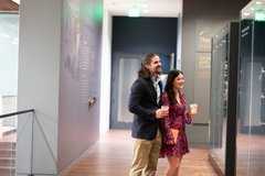 Man and a woman looking at a weapons display in a gallery