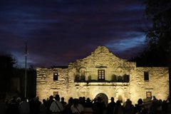 Alamo Church with visitors in the front against a dark sky