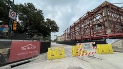 Alamo Street in front of Crockett and Woolworth Buildings with yellow barriers at street entry