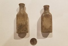 Two glass bottles, covered in dirt from an excavation