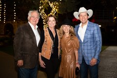 Two men and two women smiling at an outdoor, evening event