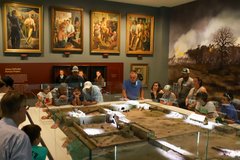 Visitors looking at a diorama of the Battle of the Alamo in a room with paintings on the wall