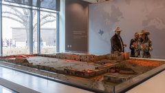 A man in a cowboy hat and two women looking at a diorama of the Battle of the Alamo