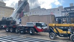 Construction truck with crane outside of building under construction