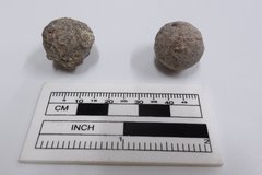 Two musket balls next to a ruler for size