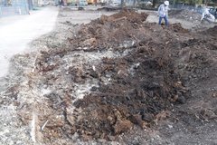 Dirt construction area with a worker in a white vest and construction hat walking through it