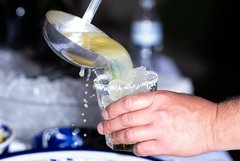 Server pouring margaritas into a glass