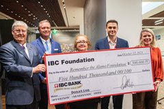 Three men and two women holding a large check