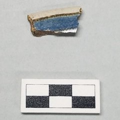 Fragment of rim sherd with a blue rim band with a brownish band outline.