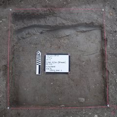 Square excavation unit with a white board and marker in the center