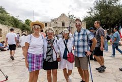 Four people wearing Alamo shaped eclipse glasses standing in front of Alamo Church