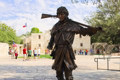 Bronze statue of David Crockett in Alamo Plaza with Alamo Church in the background
