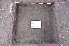 Inside of an excavation until with a whiteboard in the middle and marker at the top perimeter, lined with pink rope