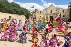 Folklorico child dancers wearing colorful dresses dancing in front of Alamo Church