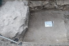 Elevated step inside an excavation unit with a whiteboard and market in the center