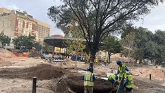 Two construction workers at Plaza de Valero construction site in front of pavilion stage
