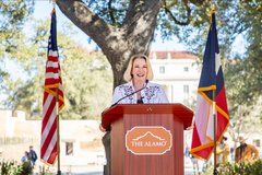 Commissioner Dawn Buckingham standing a podium flanked by US and Texas flags