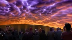 Rendering of guests in 4D theater lobby looking up at orange and purple sunset sky