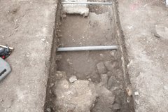 Inside excavation unit with pipe and limestone feature