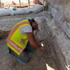 Archaeologist digging inside an excavation unit
