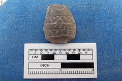 Fragment of a pipe on a blue background next to a ruler for size