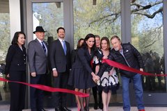 A woman holding a knife after cutting through a red ribbon in front of a building in a line with other people