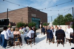Guests seated at round tables with white linens and string lights on the Alvarez Family Terrace
