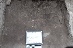 White board inside an excavation unit with a rocky border