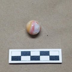 Glass marble that is opaque white with a yellow, orange, and red swirl