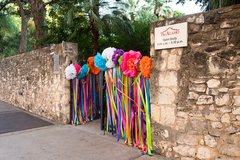 Gates to the Alamo decorated with colorful paper flowers and ribbons