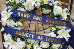 Wreath with white flowers and a blue ribbon with the words Harp and Shamrock Society of Texas