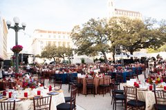Round tables set outside in Alamo Plaza under trees and string lights