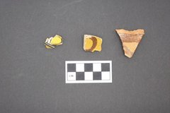 Three pieces of ceramics on a gray surface next to a ruler for size