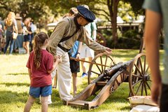 Living Historian showing a cannon to a young girl