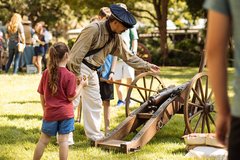Living Historian showing a cannon to a young girl